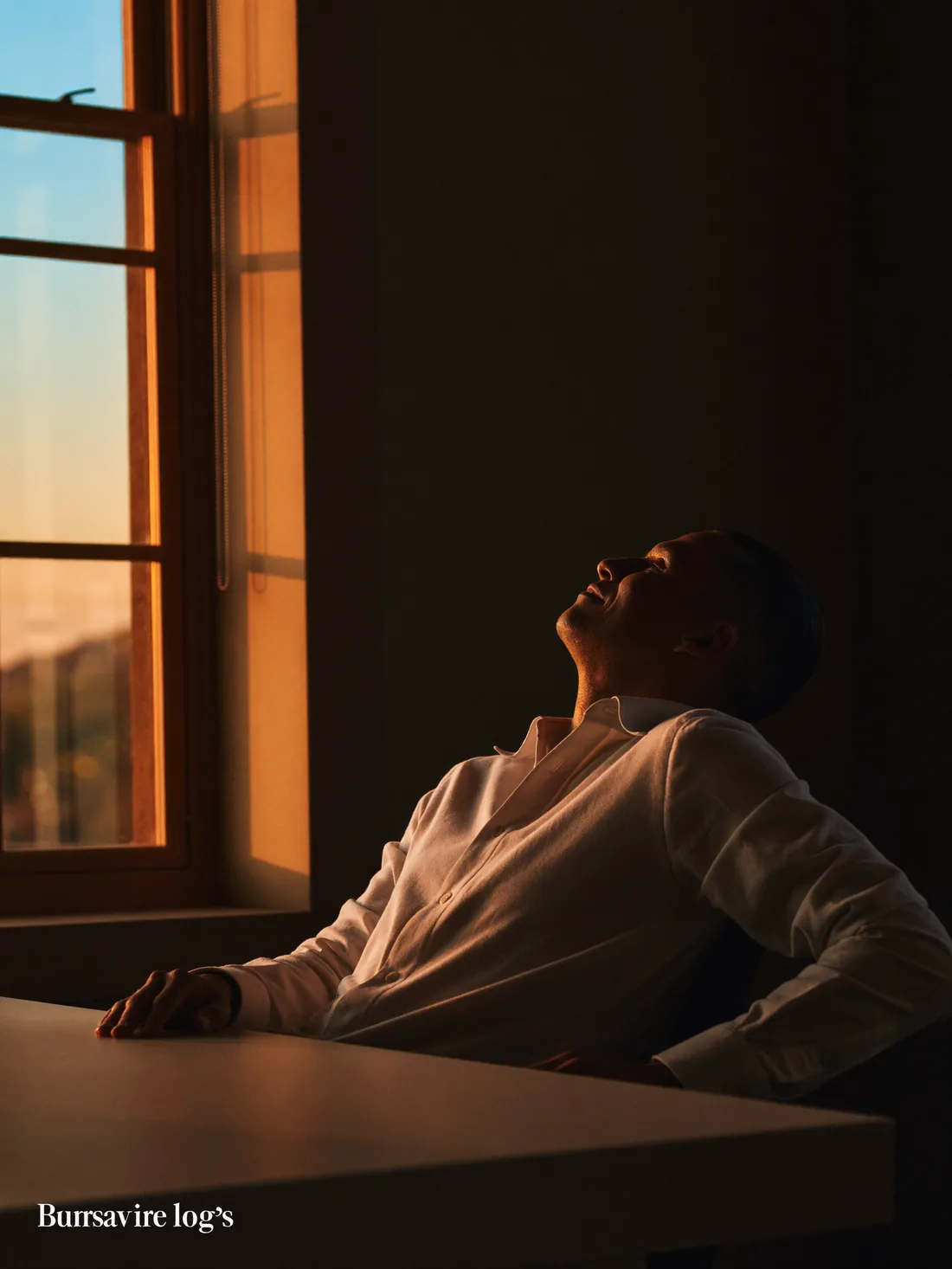 An executive in confident stillness at a warm-lit desk at dawn, sharp and recovered